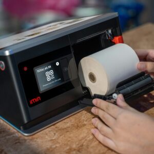 Hands setting up a thermal roll in a point-of-sale touchscreen device.